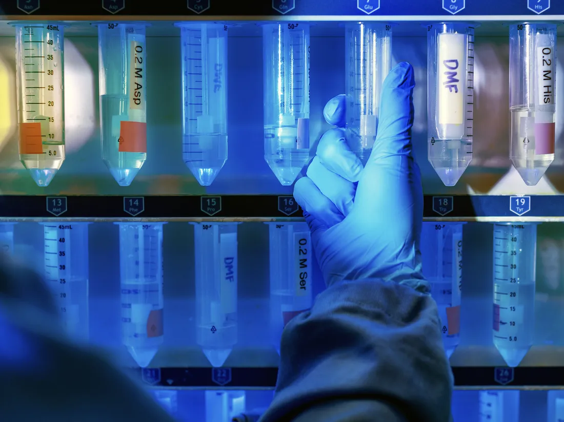 Gloved hand holds test tube equipment in lab.