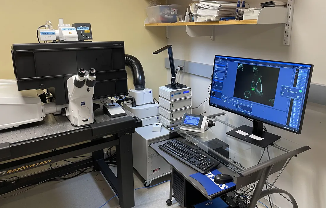 Computer on desk with other lab equipment surrounding it.