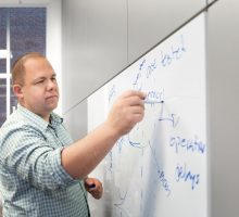 Professor David Larsen draws a graph on a white board in his office.